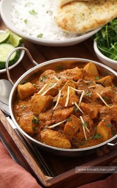 some food that is in a pan on a wooden tray with rice and other foods