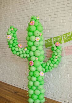 a cactus made out of balloons sitting on top of a wooden floor