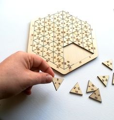 a person is playing with wooden puzzles on a white surface and several pieces are scattered around