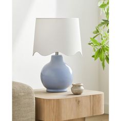 a blue vase sitting on top of a wooden table next to a white lampshade