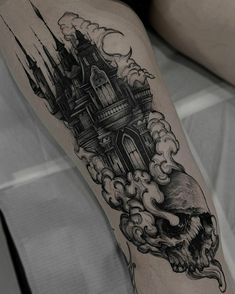 a woman's leg with a castle and skull tattoo on it