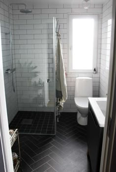 a white toilet sitting in a bathroom next to a walk in shower and sink under a window