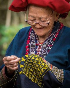 an old woman wearing a red hat and holding a piece of cloth in her hands