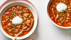 two bowls of chili and bean soup with sour cream on top, one bowl is empty