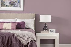 a bedroom with purple walls and white trim on the headboard, nightstands, and bed