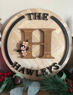 a wooden sign with the letter h on it sitting next to some christmas decorations and greenery