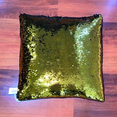 a green sequin pillow sitting on top of a wooden floor