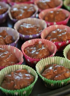 there are many cupcakes with chocolate frosting in the cups on the tray