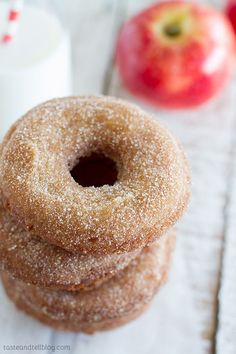 two sugary donuts stacked on top of each other with an apple in the background