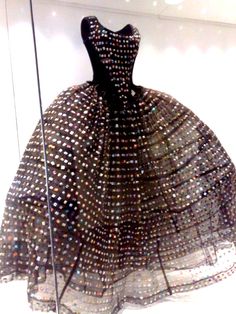 a dress that is on display in a glass case with some kind of material behind it