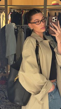 a woman taking a selfie with her cell phone in front of some clothes on racks