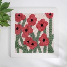 crocheted red flowers on white background with green leaves