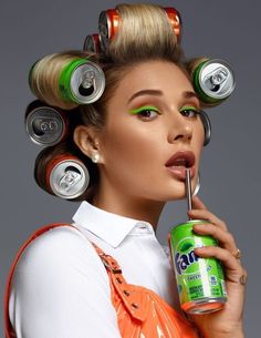 a woman with cans on her head and green eyeshade holding a can of soda