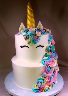 a white cake topped with a rainbow colored unicorn's horn and swirly icing