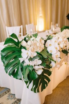 the table is set with white flowers and greenery for an elegant wedding reception in santa monica, california