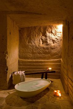 a bath tub sitting in the middle of a bathroom next to a table with candles on it