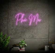 a pink neon sign that says pho me on the wall next to a potted plant