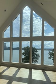 an empty room with large windows overlooking the water