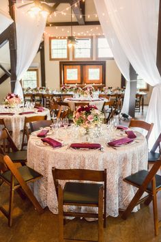 the tables are set up for an event with white drapes and pink napkins