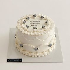 there is a white cake with silver decorations on the top and bottom, sitting on a plate