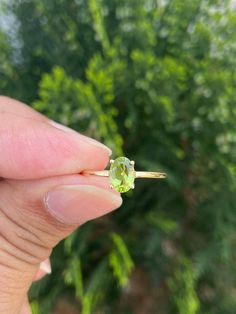 a person holding an engagement ring with a green diamond in it's middle finger