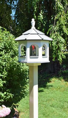 a white bird house with a red rose in the window