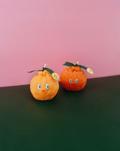 two oranges sitting on top of a table with faces painted on them and one has eyes