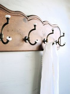 a coat rack with three coats hanging from it's sides and two hooks on the wall