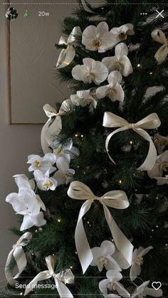 a christmas tree decorated with white flowers and ribbons