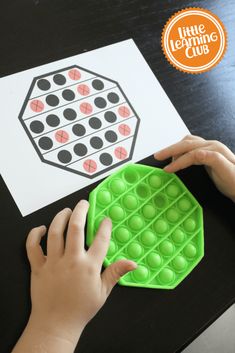 a child's hand on a green plastic tray next to a printable puzzle