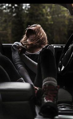 a woman sitting in the back seat of a car with her hand on her head