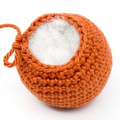 an orange and white crocheted ball on a white background