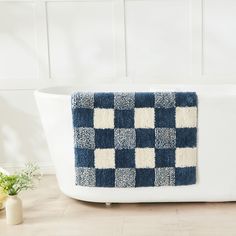 a bath tub with a blue and white checkered towel on it's side