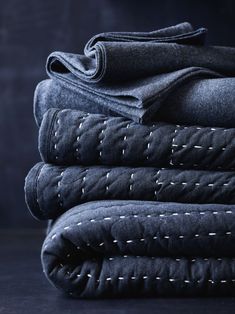 several folded denims stacked on top of each other with stitching at the edges