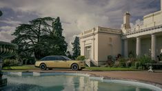 a yellow car parked in front of a large house next to a fountain with water