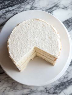 a white cake on a plate with one slice cut out and ready to be eaten