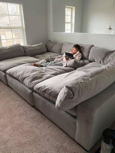 a person laying on top of a couch with a book in their hand and looking at it