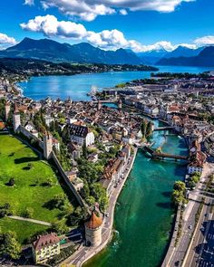 an aerial view of a river running through a city next to a lush green hillside