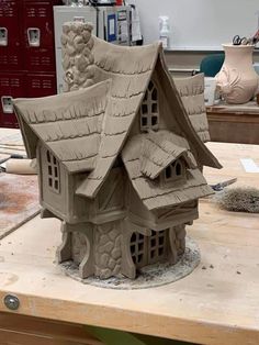 a clay house sitting on top of a wooden table