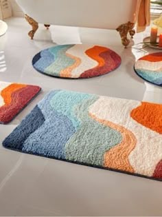 colorful bathroom rugs on the floor in front of a bathtub and sink area