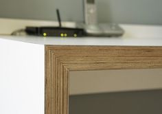 a close up of a wooden frame on a white counter with a cell phone in the background