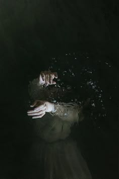 a person floating in the water with their hands on his chest and one hand reaching for something