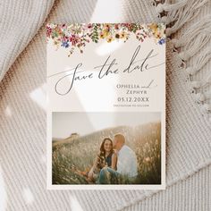 the save the date card is laying on top of a blanket with an image of two people