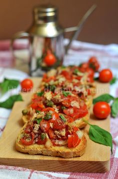 bread topped with tomatoes and basil on a cutting board