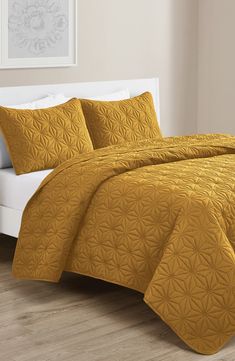 a bed with yellow bedspread and pillows