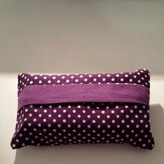 a purple and white polka dot pillow sitting on top of a table next to a wall