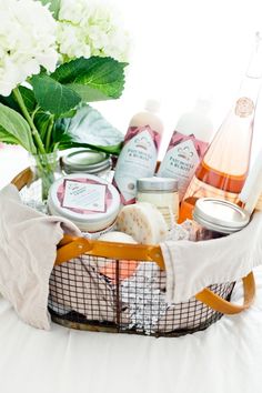 a basket filled with personal care items on top of a white bed next to flowers