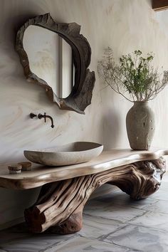 a wooden table sitting next to a mirror and vase on top of a stone floor