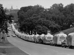 a long line of trailers parked on the side of a road next to some trees