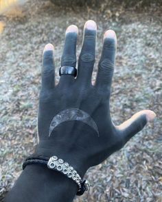 a person's hand wearing a black leather bracelet with a crescent moon on it